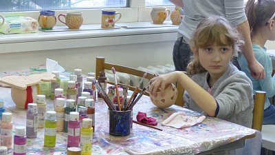 Dívenka zkouší namalovat keramický výrobek